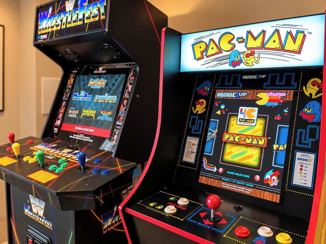 Two arcade machines, one for WWE and one for Pac-Man, with joystick controls and colorful graphics.