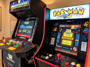Due macchine arcade, una con WWE e una con Pac-Man, dotate di comandi a joystick e grafica colorata.