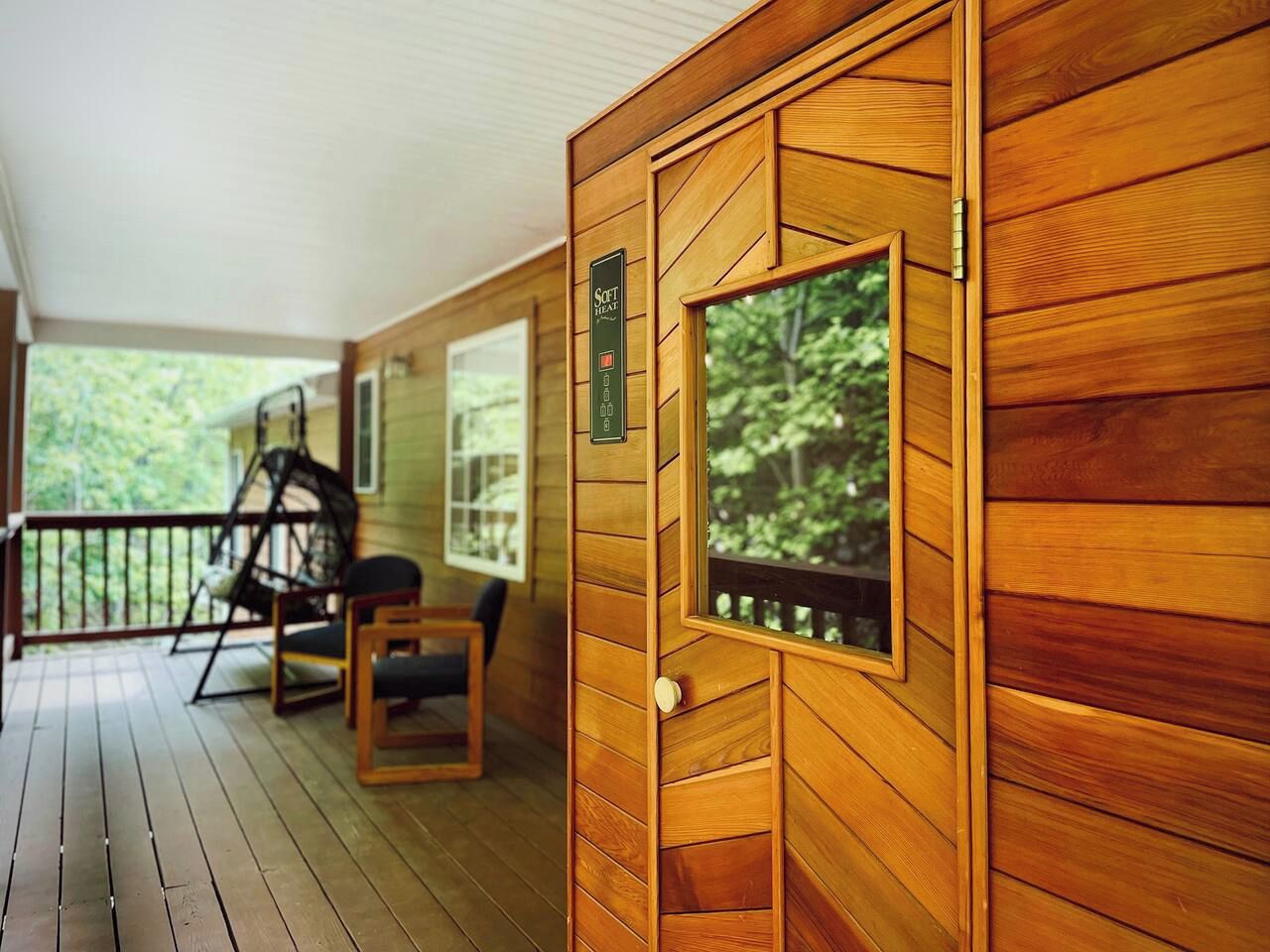 A wooden cabin with a porch, a swing chair, and a small table.