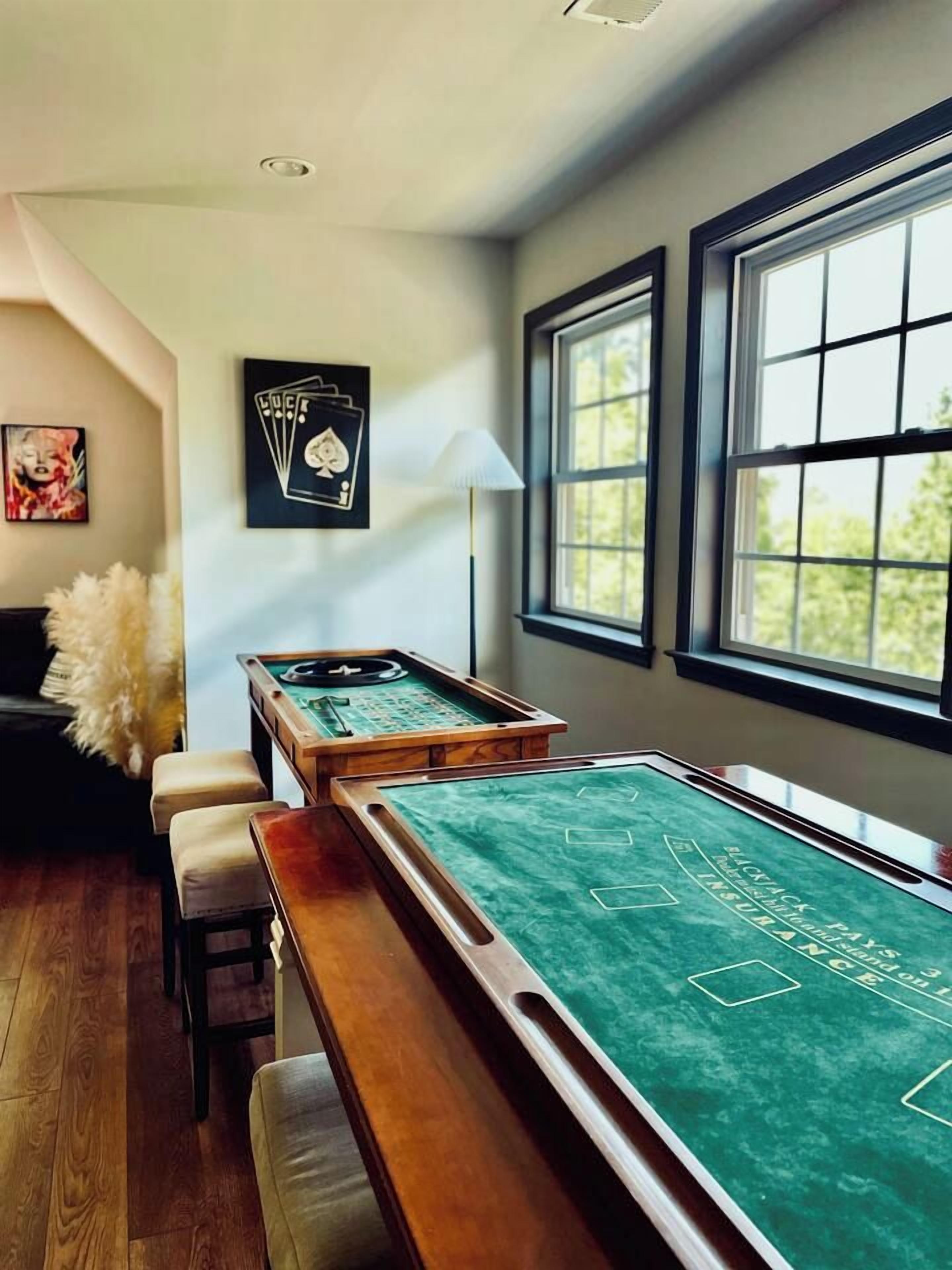 A pool table with a chalkboard surface, a lamp, and a framed poker set on the wall.