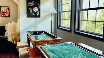 A pool table with a chalkboard surface, a lamp, and a framed poker set on the wall.