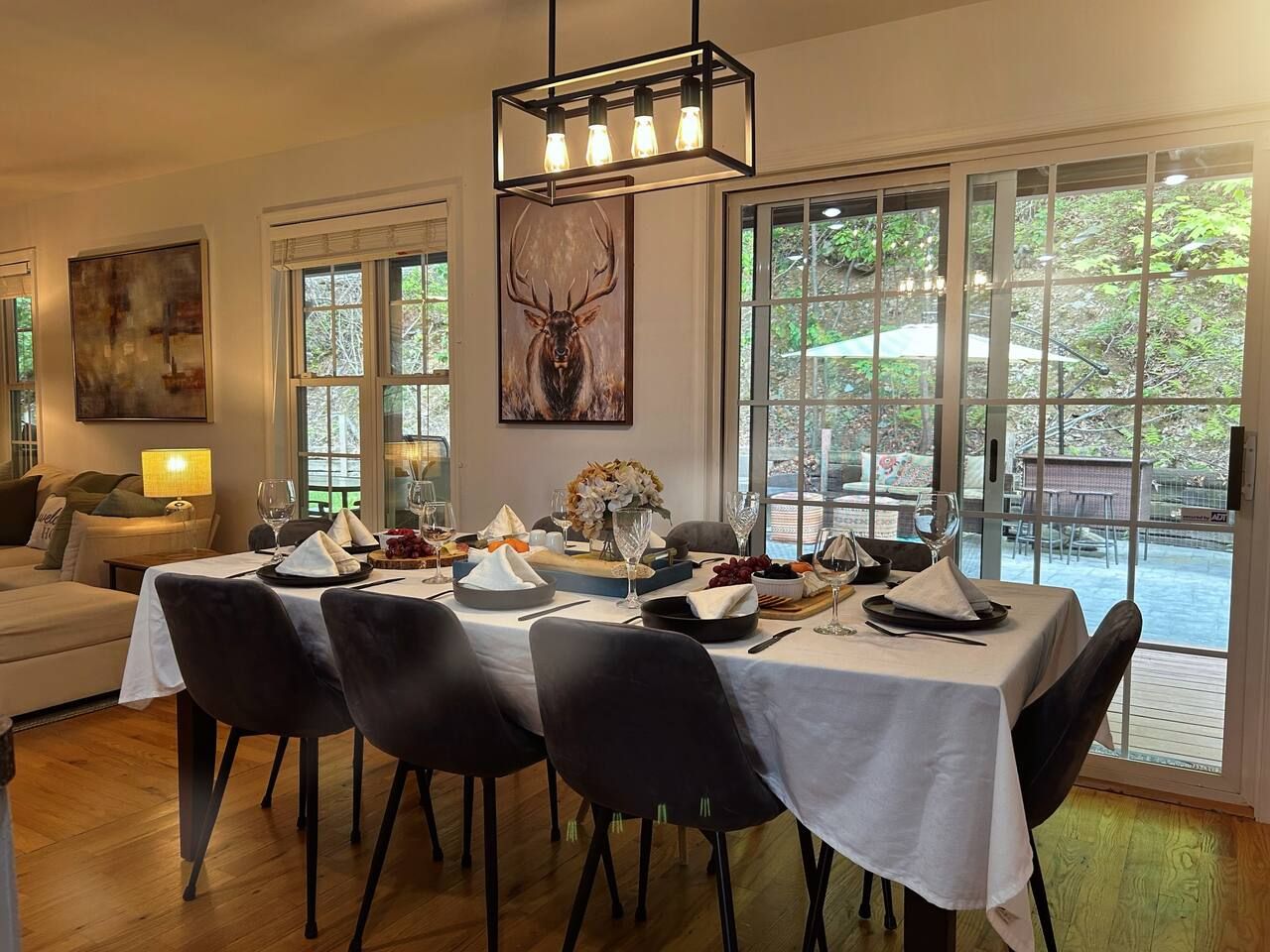 Un coin repas avec une table dressée pour quatre personnes, entourée de chaises, et une grande fenêtre donnant sur l’extérieur.