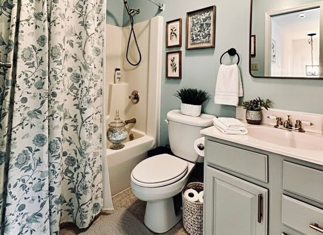 Ein Badezimmer mit Toilette, Waschbecken und Dusche. An der Wand befinden sich gerahmte Bilder und ein Handtuch hängt dort.