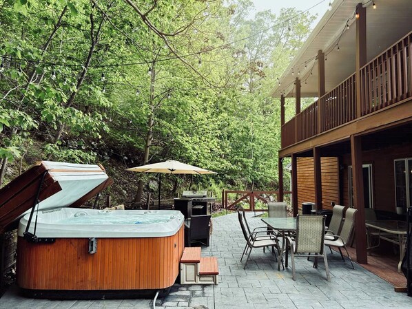 An outdoor patio with a hot tub, dining area, and a covered seating area.