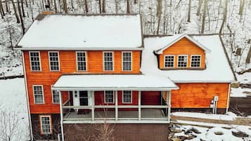 A two-story house with a porch and a detached garage, surrounded by a snowy landscape.