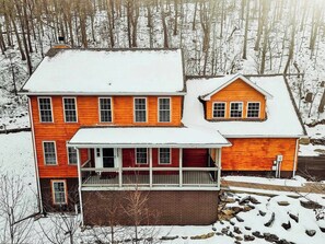 A two-story house with a porch and a detached garage, surrounded by a snowy landscape. - The RidgeView Retreat-HotTub Sauna Forest Patio (Harpers Ferry)