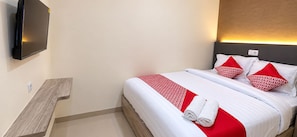 Habitación de hotel con una cama, un televisor de pantalla plana montado en la pared y una mesita de noche de madera.
