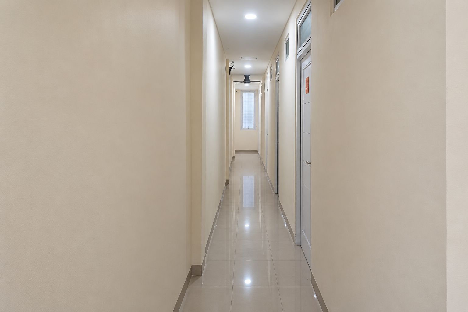 Un pasillo largo y estrecho con piso de baldosas y un ventilador de techo.