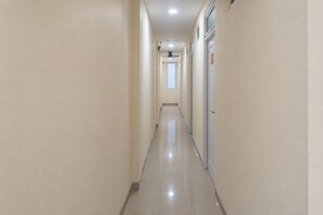 A long, narrow hallway with a tiled floor and a ceiling fan. - Collection O Noura Family Residence (Malang)