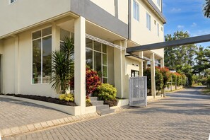 Un edificio moderno de dos pisos con amplios ventanales, un acceso cubierto y un camino de entrada pavimentado.