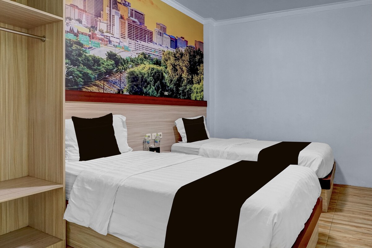 Habitación de hotel con dos camas, un armario de madera y un mural con vista a la ciudad.