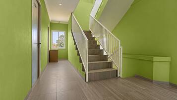 A hallway with a staircase, green walls, and a door on the left.