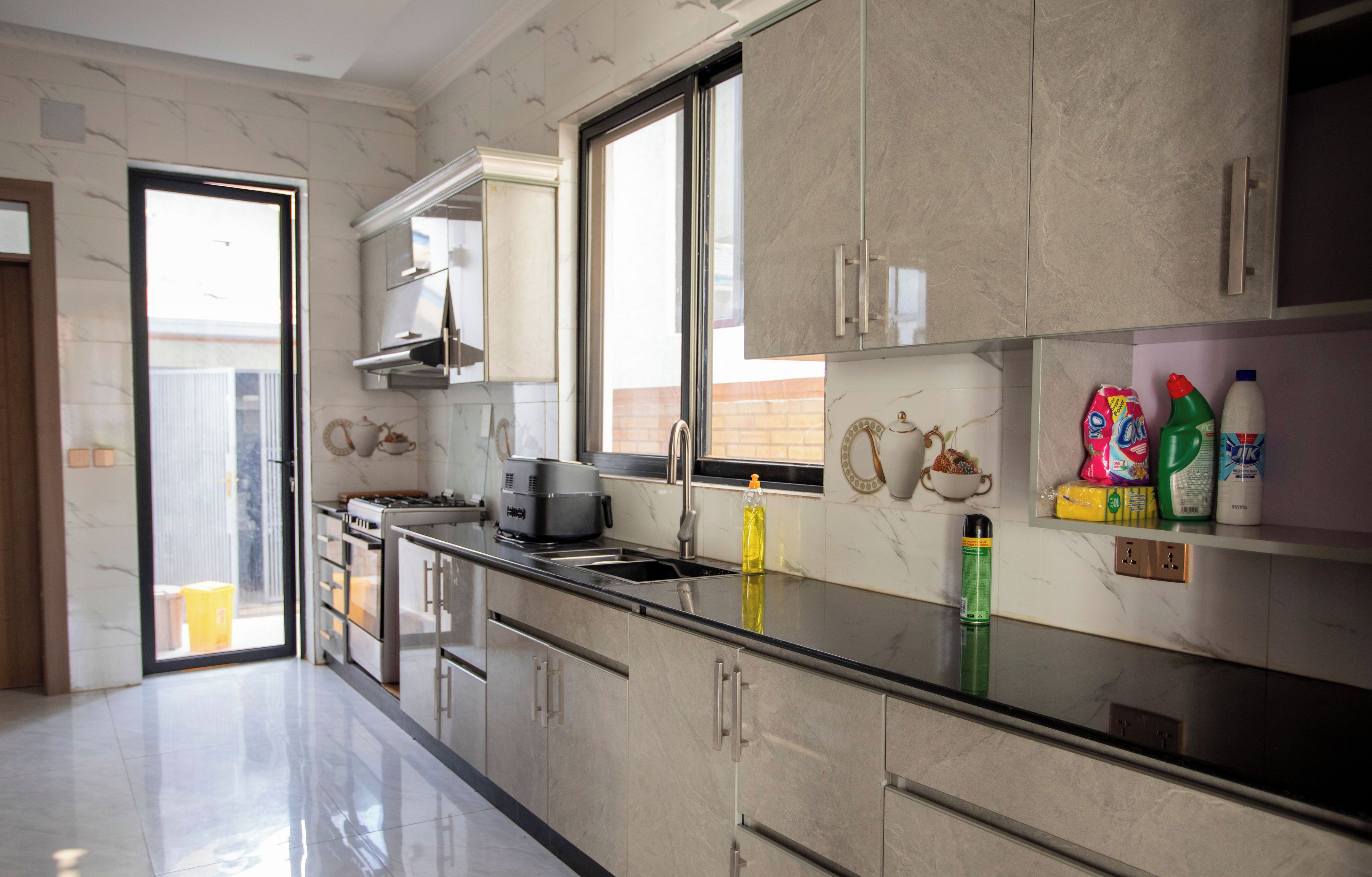A modern kitchen with a stainless steel countertop, a built-in oven, and a window providing natural light.