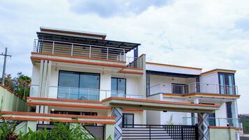 A modern two-story house with a gated entrance, large windows, and a balcony.