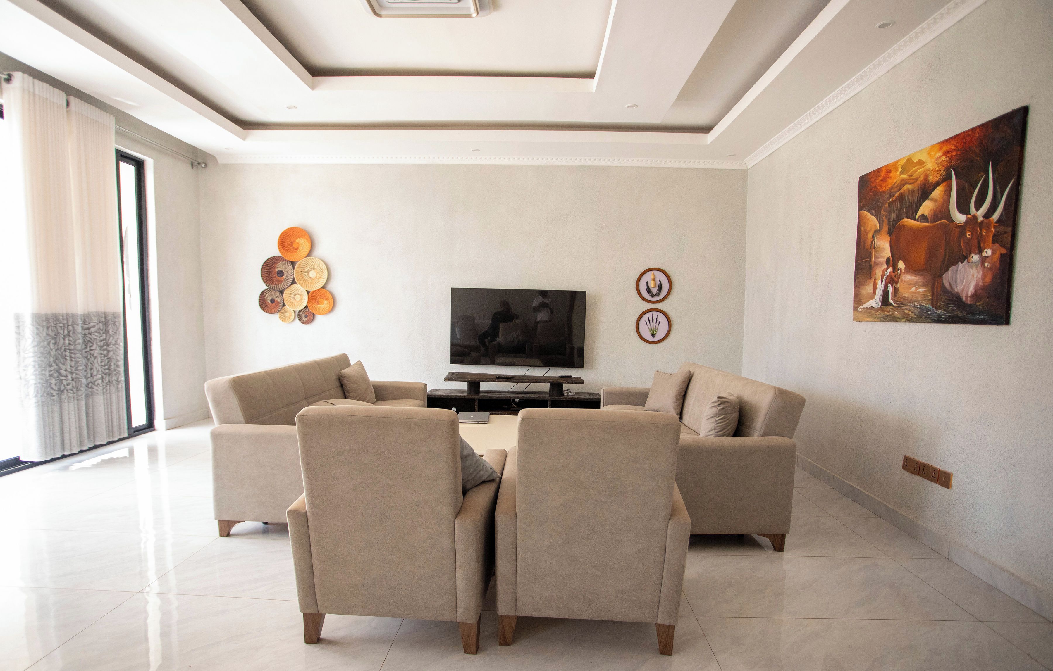 Una sala de estar moderna con un televisor de pantalla plana, dos sofás, una mesa de centro y decoración mural.