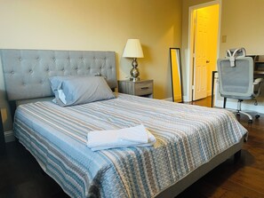 A neatly made bed with a striped bedspread, a bedside lamp, and a chair with a backrest. -  Spacious 2-story 6-bedroom House Perfect for Families & Work Groups (Melissa)