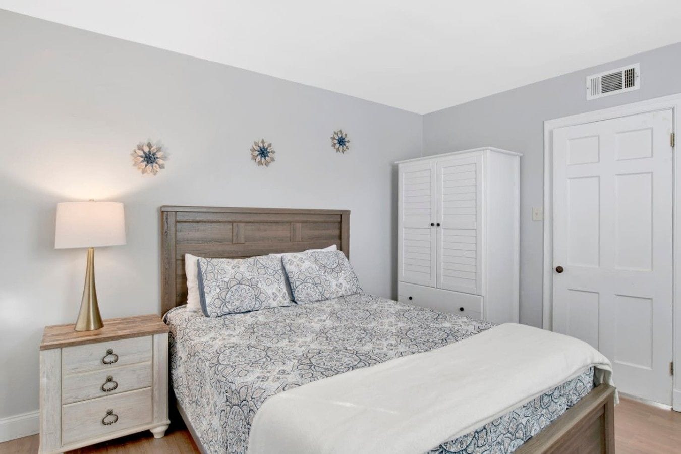 A bedroom with a bed, a nightstand, a dresser, and a wardrobe.