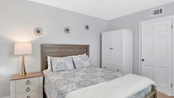 A bedroom with a bed, a nightstand, a dresser, and a wardrobe.