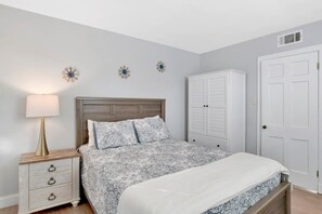 A bedroom with a bed, a nightstand, a dresser, and a wardrobe. - Southern Comfort (Mobile)