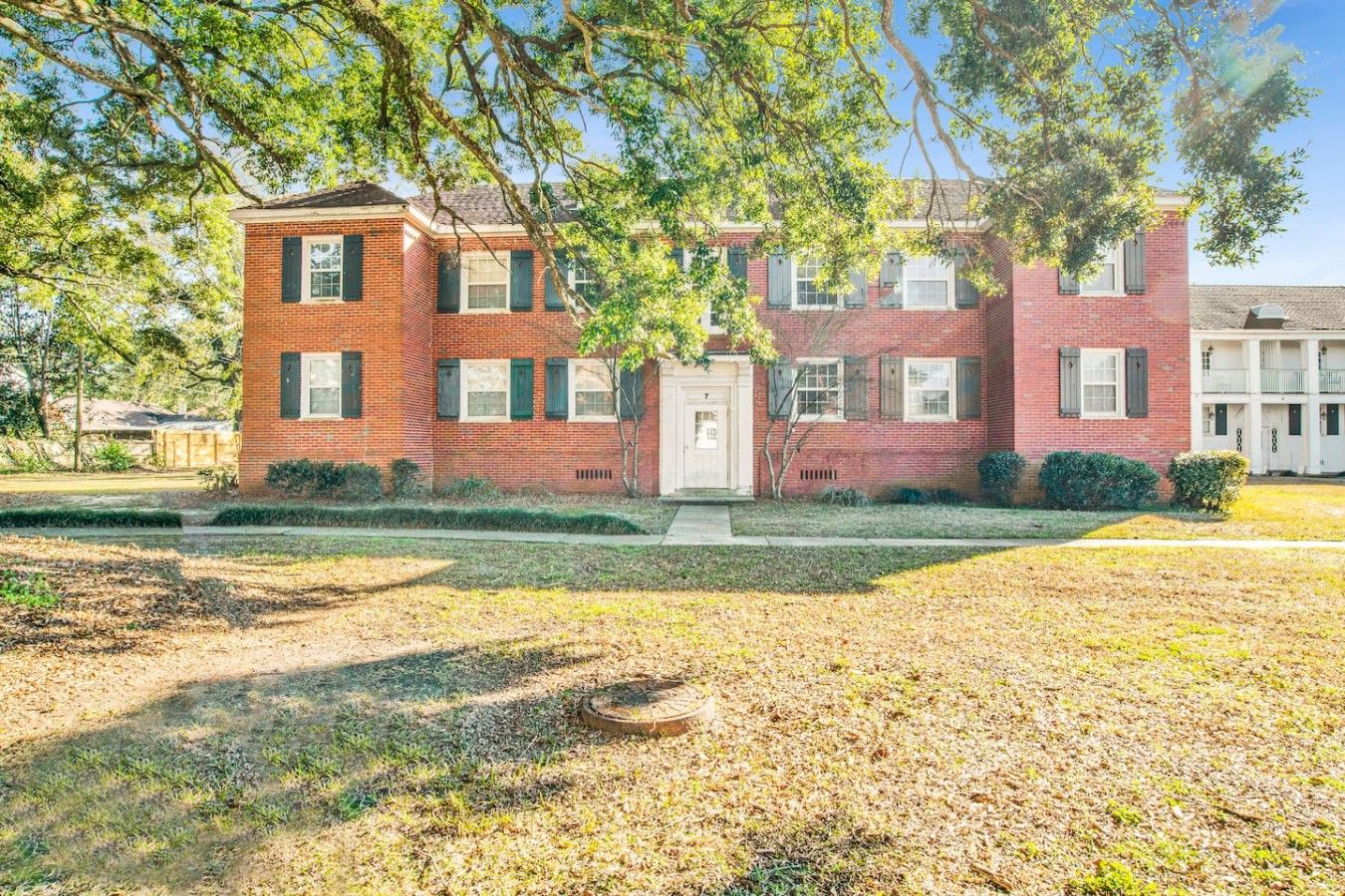A two-story brick building with a front door, windows, and a small front yard.
