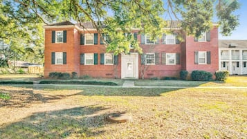A two-story brick building with a front door, windows, and a small front yard.