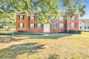 A two-story brick building with a front door, windows, and a small front yard. - Southern Comfort (Mobile)