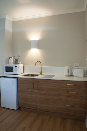A modern kitchen with a built-in microwave, a stainless steel sink, and a kettle on the countertop. - The Palms Tocumwal (Tocumwal)