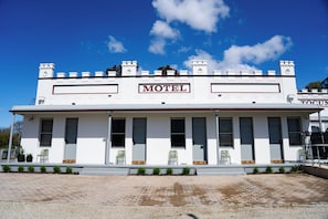 Un edificio blanco con un letrero que dice 'Motel' y un letrero más pequeño que dice 'TOCUM'.