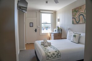 A hotel room with a bed, a microwave, a small table, and a window with a view of the street.