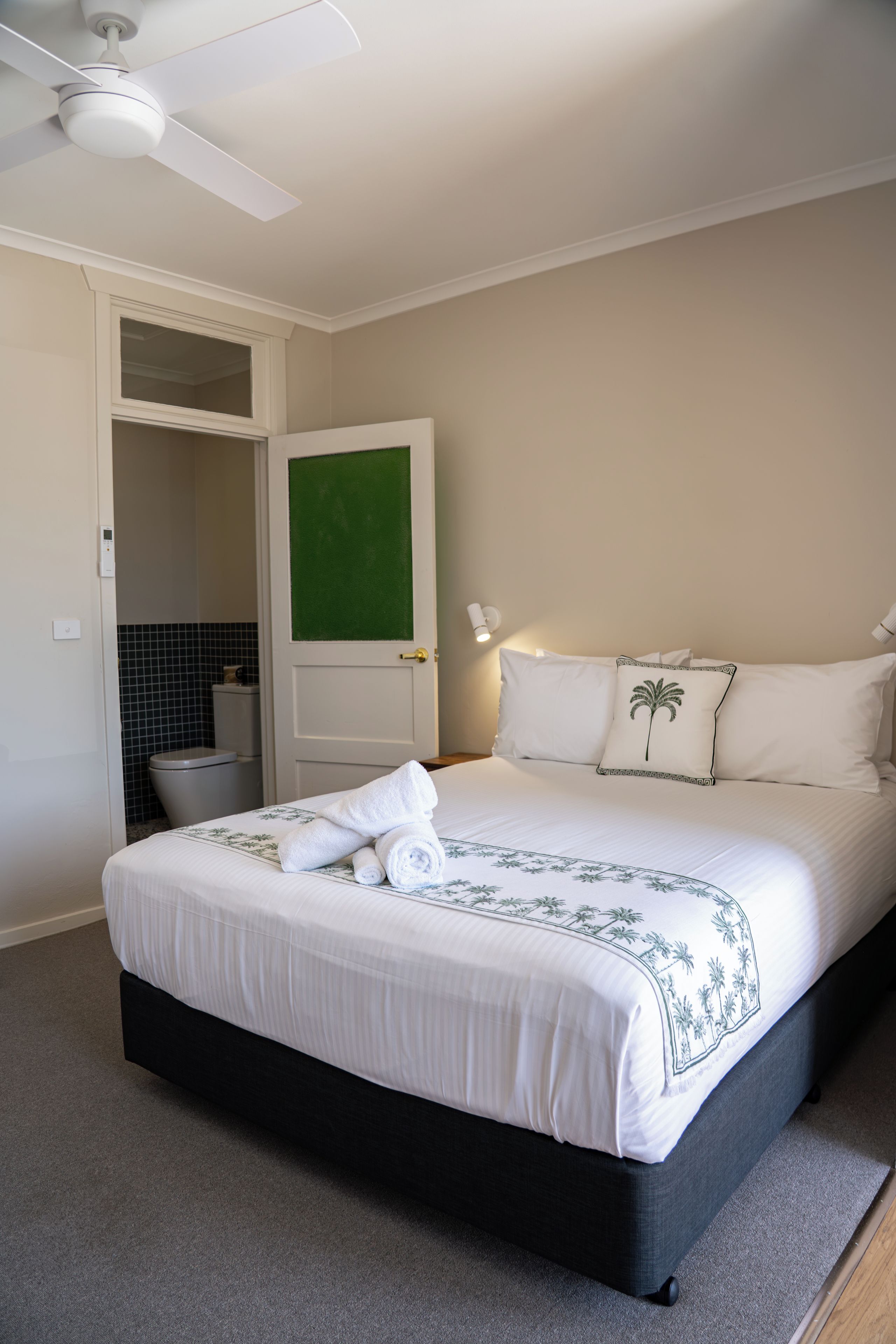 A hotel room with a bed, a bathroom, and a ceiling fan.