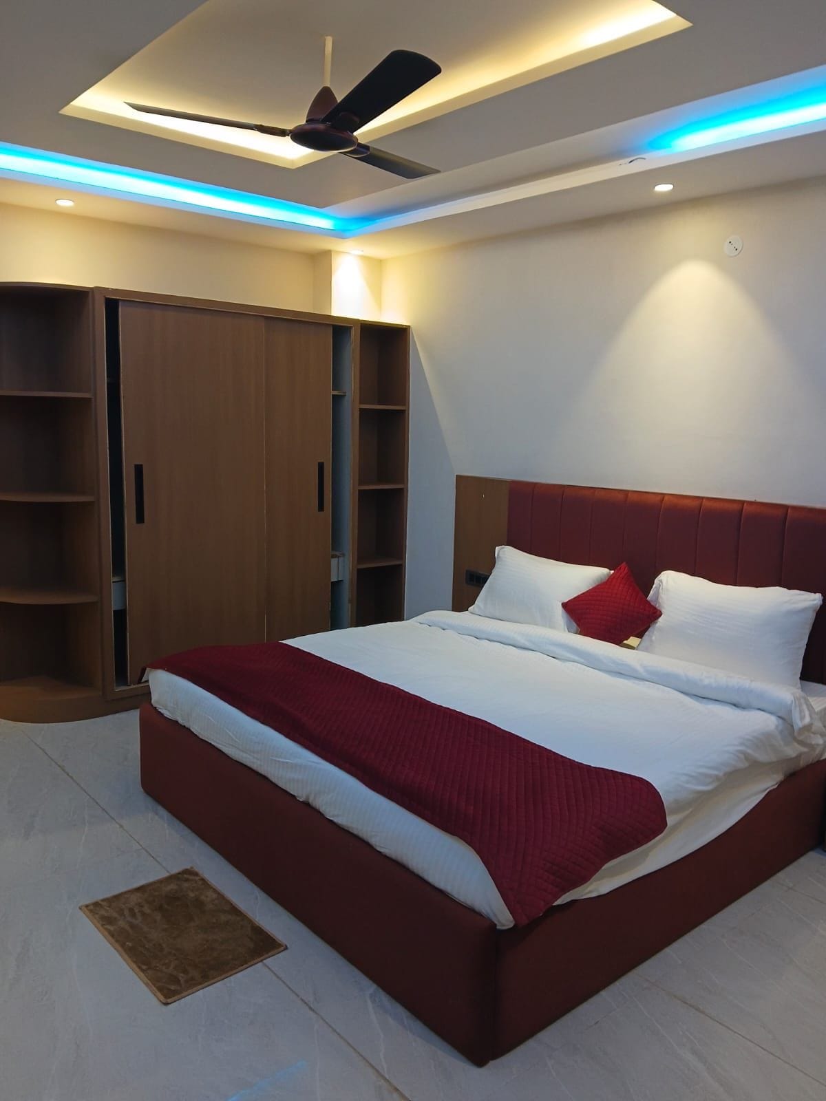 Une chambre moderne avec un lit, un ventilateur de plafond et des étagères intégrées.