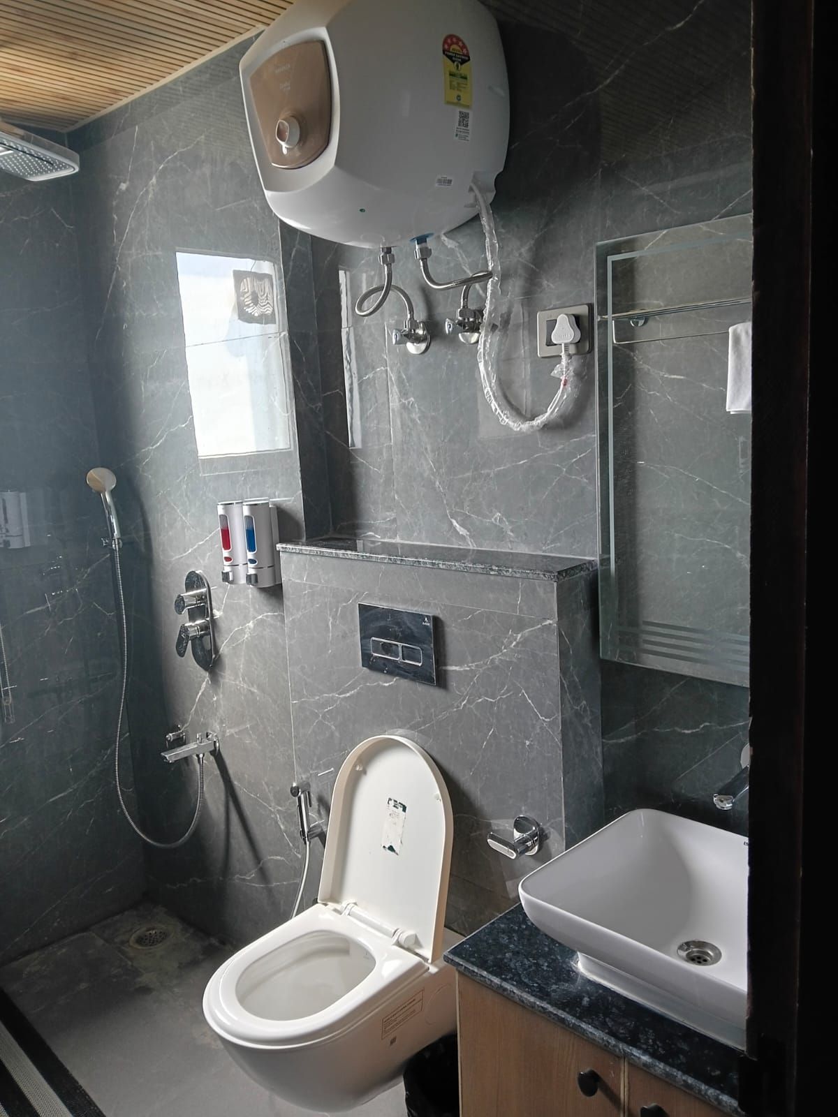 Un baño con inodoro, lavamanos, ducha y calentador de agua.
