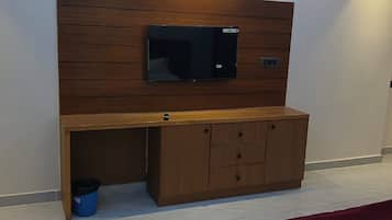 Una habitación de hotel con una cama, un escritorio de madera con un televisor y un reloj en la pared.