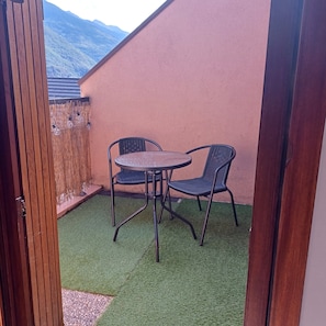 Eine Terrasse mit Tisch und Stühlen, ein Holzzaun und Blick auf die Berge.