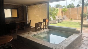 A modern outdoor pool area with a glass enclosure, a dining table, and lounge chairs.