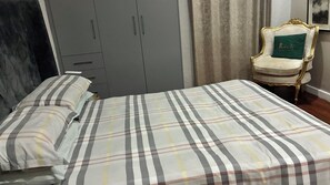A bedroom with a bed, a wardrobe, and a chair.