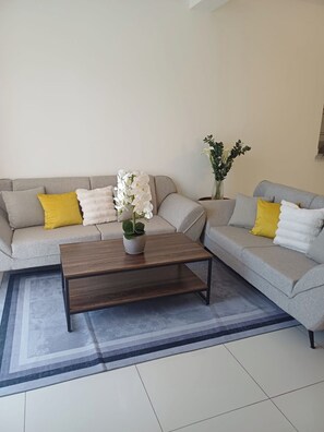 A living room with two grey sofas, a wooden coffee table, and a patterned rug. - Sunset: 3 Queen Bedrooms, Pool & Gym, Beach Across the Street (Puerto Plata)