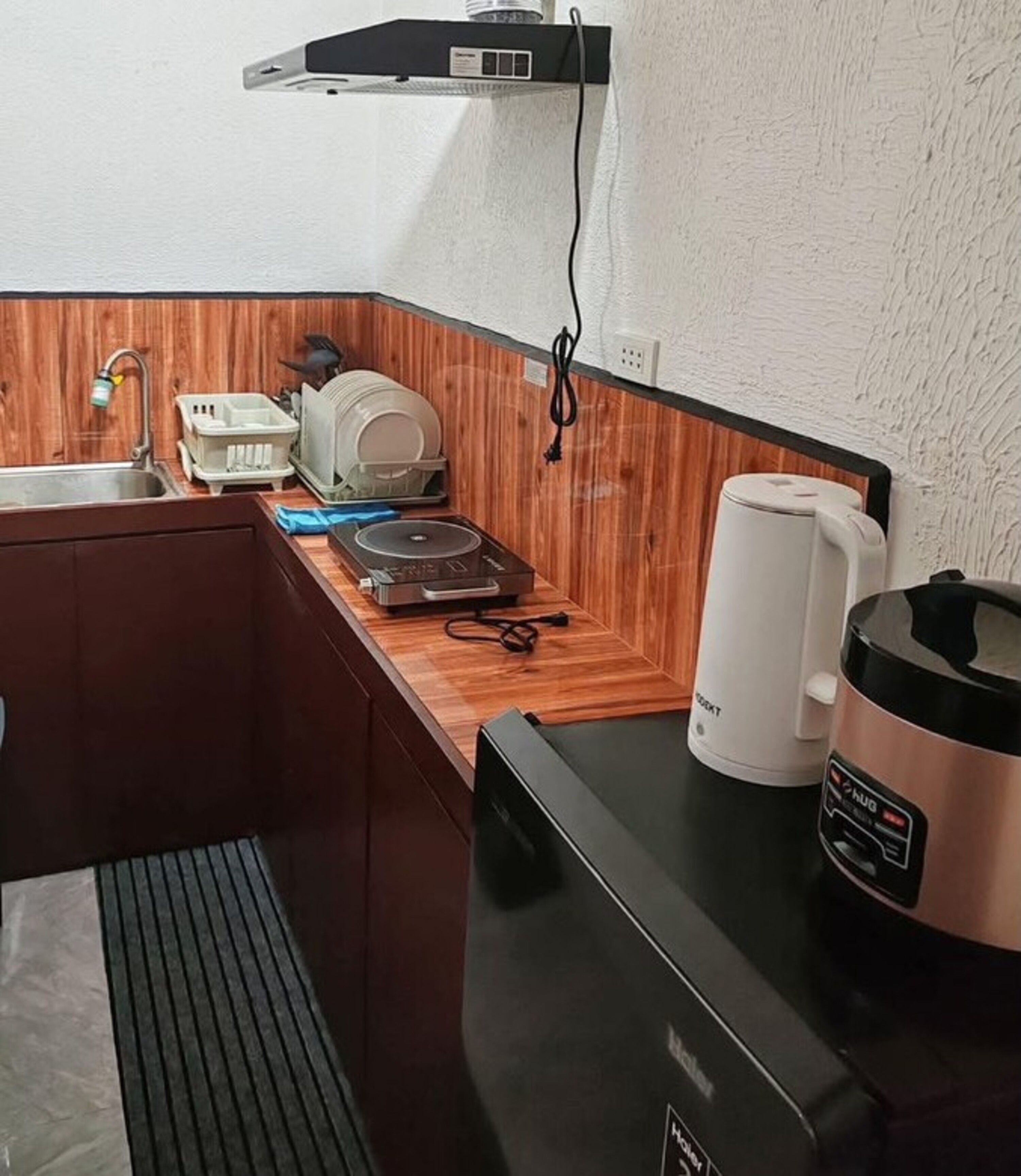 A compact kitchen with a sink, a coffee maker, a kettle, and a small refrigerator.