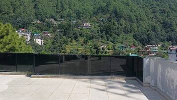 A rooftop terrace with a view of a densely forested hillside.