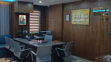 A conference room with a long table, multiple chairs, and a wooden wall with a framed picture.