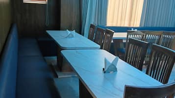 A dining area with a long table and benches, a window with blinds, and a ceiling with a skylight.