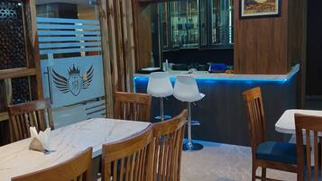 A dining area with wooden chairs and a table, a bar with a counter and stools, and a ceiling fan.