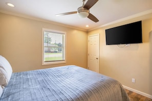A bedroom with a bed, a ceiling fan, a window with blinds, a door, and a mounted TV. - Private Backyard• Free Parking• Grill• Deck (Birmingham)