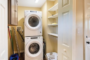 A laundry area with two stacked washing machines, a mop, a broom, and a laundry basket. - Private Backyard• Free Parking• Grill• Deck (Birmingham)