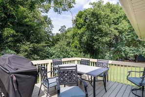 An outdoor deck with a table and chairs, surrounded by trees. - Private Backyard• Free Parking• Grill• Deck (Birmingham)