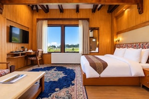 A hotel room with a large bed, a desk, a television, and a view of the outdoors. - House of Khazir (Gulmarg)