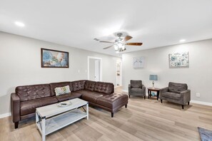 A living room with a sectional sofa, two armchairs, a coffee table, and a ceiling fan. - Flint Ridge (Mobile)