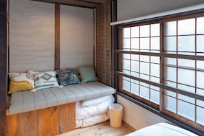 Ein Zimmer mit einer fest eingebauten Sitzbank, einem Fenster mit Milchglas und einem Holzboden.
