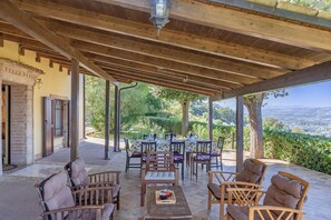 An outdoor patio with wooden furniture and tables, a view of the countryside, and a covered area with a wooden ceiling. - Villa Stefano by Anita Villas (Campofilone)