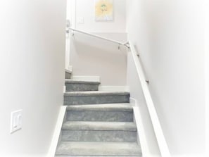 Una escalera con barandilla y un aplique en la pared.